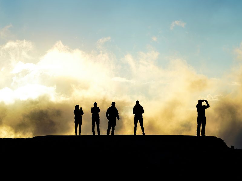 Cinco personas de pie sobre la cima de una loma, en silueta contra un cielo al atardecer. Foto: Csaba Veres / Unsplash